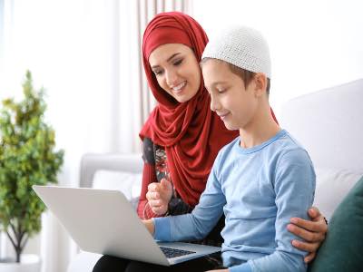 Muslim woman using laptop with her son at home